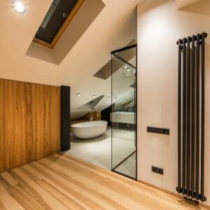 Interior of modern bathroom with wooden elements near entrance and bright illumination over bathtub